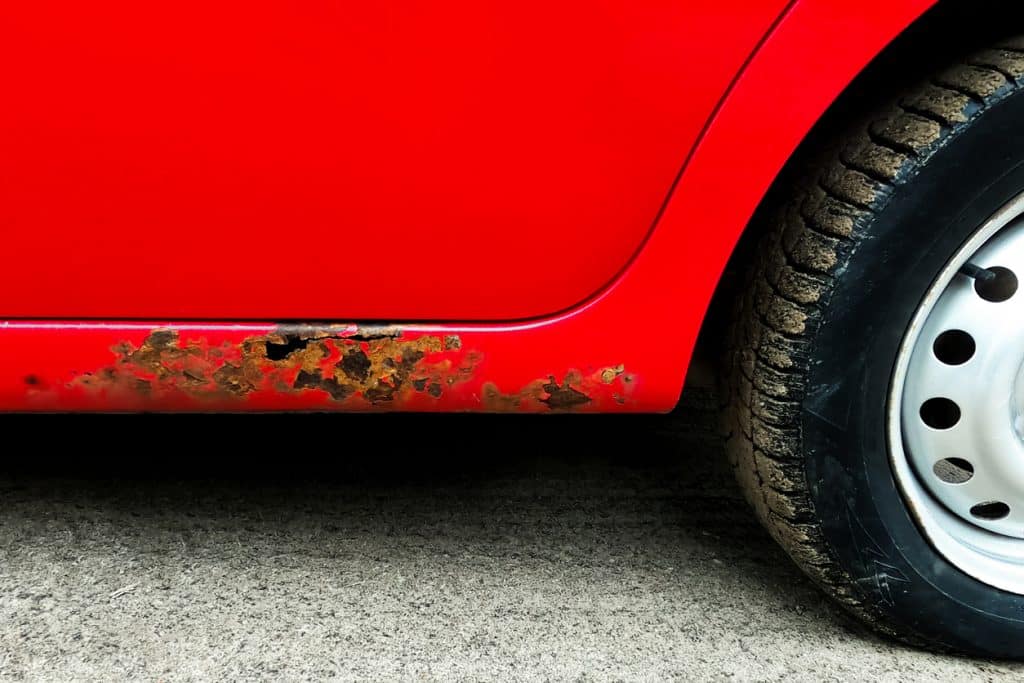 Óxido en la carrocería del coche. Una vista del saeredi. Rojo. Fragmento de la rueda.